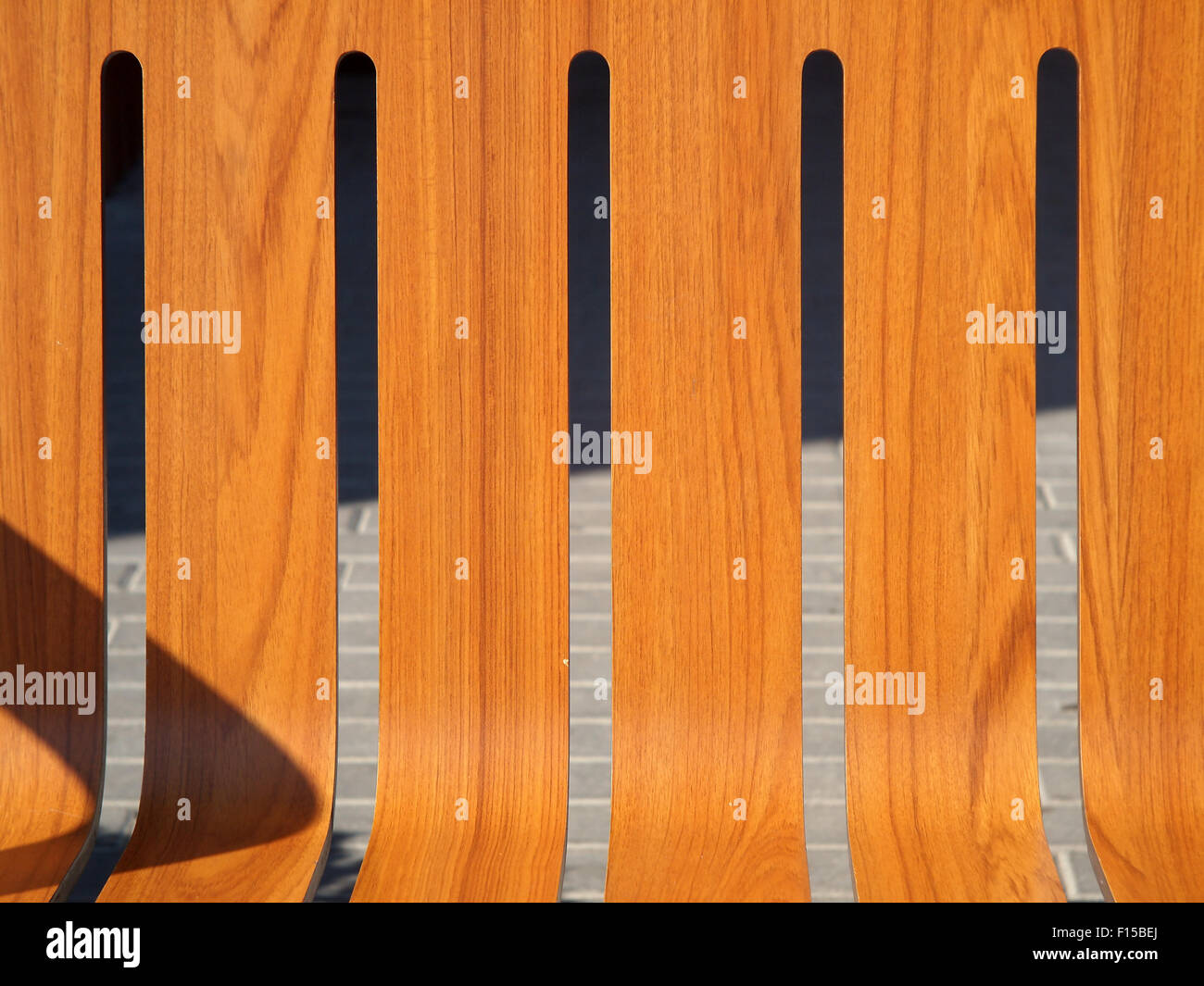 Il sedile è panche di legno sulla strada closeup e ombra dal retro illuminato sole luminoso con pavimentazione in background Foto Stock