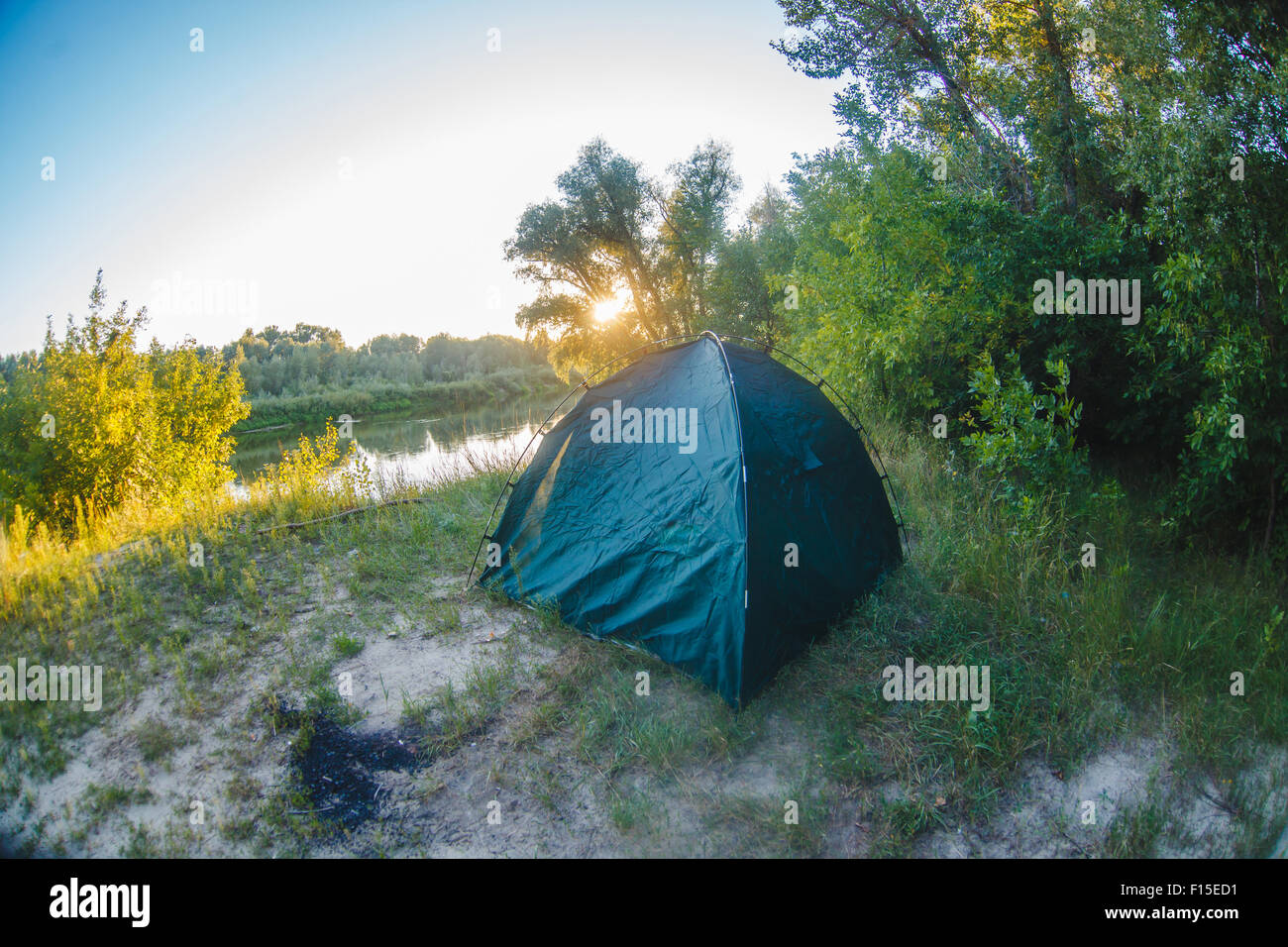 Tempo libero tenda sorge sulle rive del fiume al tramonto del sole Foto Stock