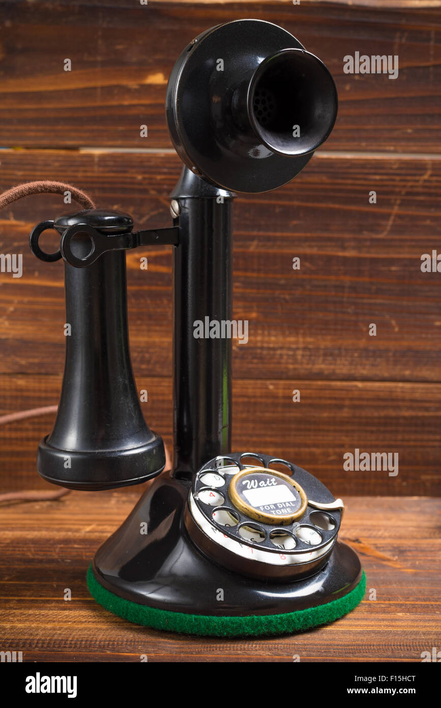 Un vintage, di vecchio stile antico candeliere telefono su uno sfondo di legno Foto Stock