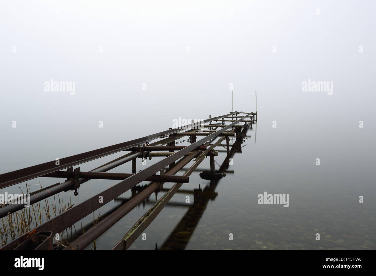 Un vecchio molo dalle sponde del Loch Lomond nella nebbia Foto Stock