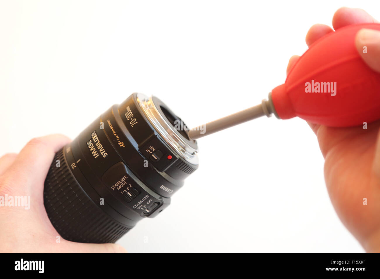 Utilizzando la pompa aria per pulire la lente della fotocamera su sfondo bianco Foto Stock