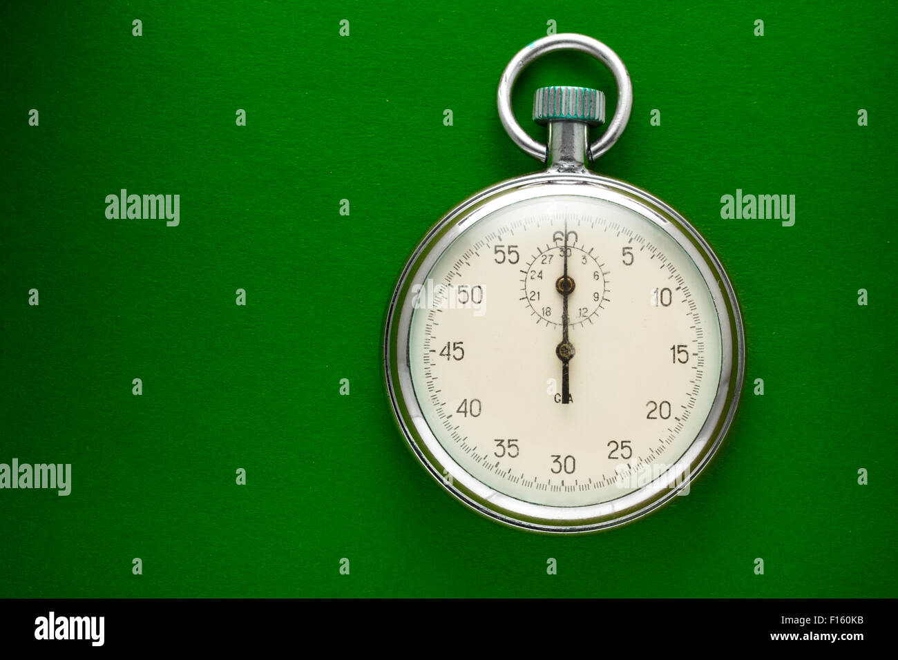 Unico cronometro closeup sul libro verde sullo sfondo Foto Stock