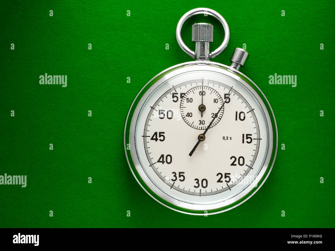 Unico cronometro closeup sul libro verde sullo sfondo Foto Stock