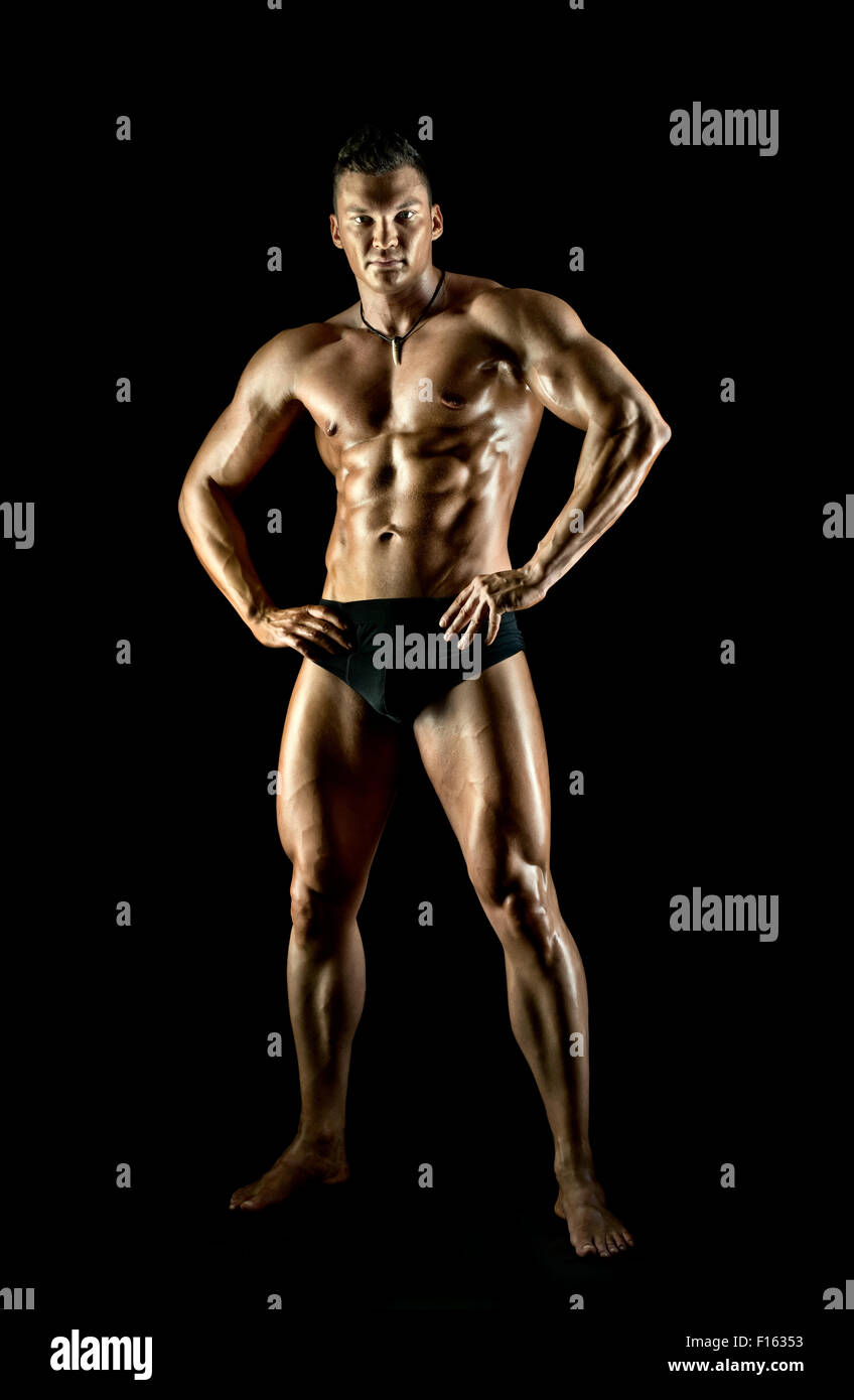 Il muscoloso bello sexy guy su sfondo nero e a piena lunghezza Foto Stock