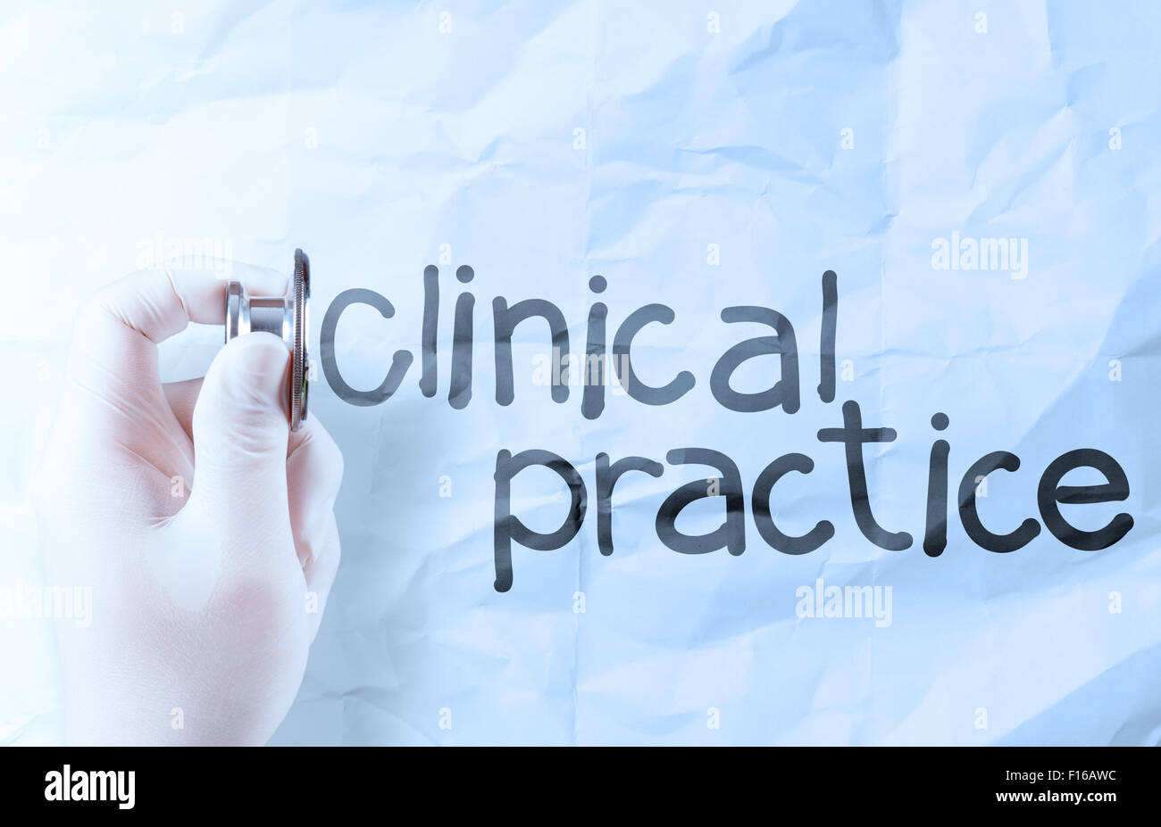 Tenere in mano uno stetoscopio che mostra la pratica clinica parole su carta sgualcita sfondo Foto Stock