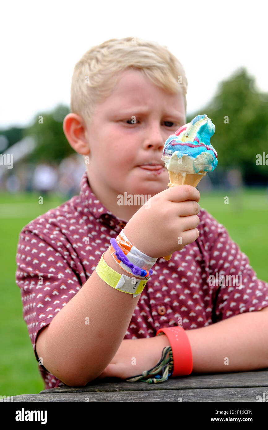 6 anno vecchio ragazzo leccare le labbra mentre mangiare un gelato cornet con aggiunta di aromatizzanti Foto Stock