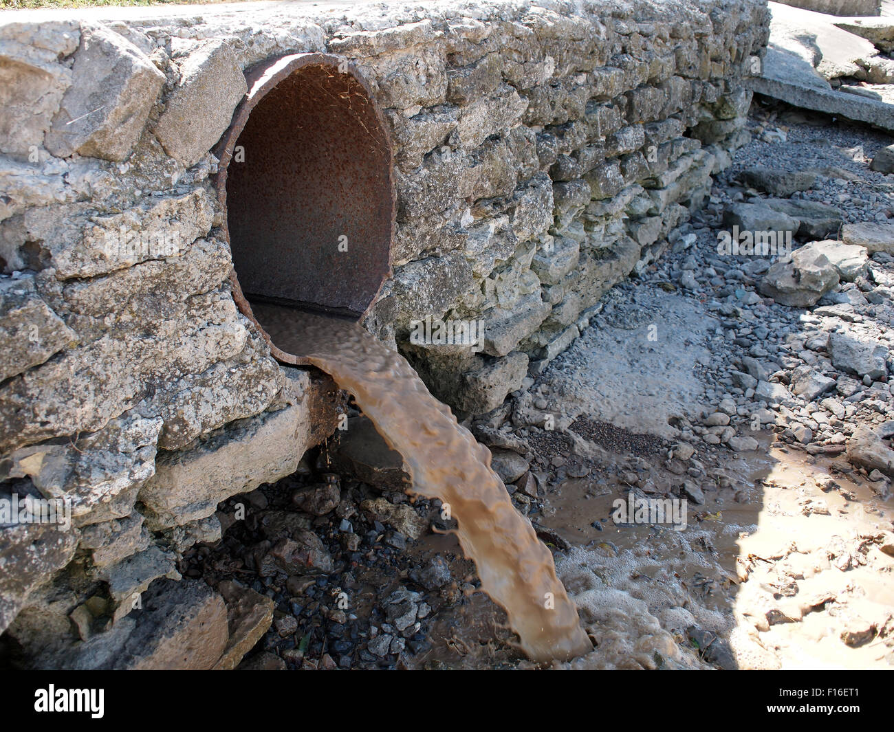 Messa a fuoco selettiva. Acqua sporca fluisce da un marrone arrugginito di fognature tubazioni di grande diametro Foto Stock