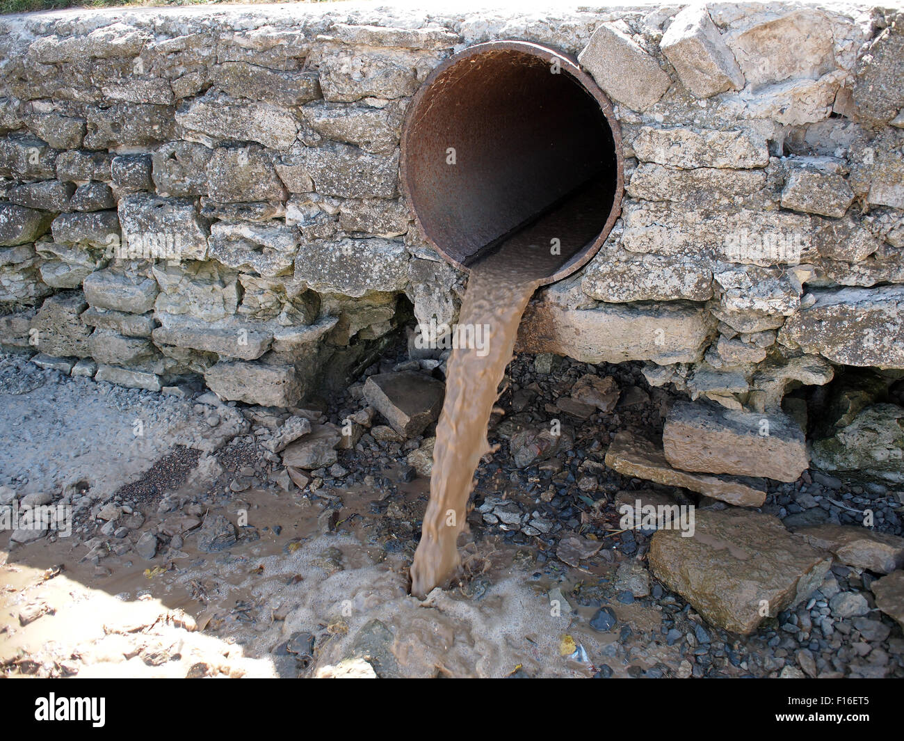 Acqua sporca fluisce da un marrone arrugginito di fognature tubazioni di grande diametro Foto Stock