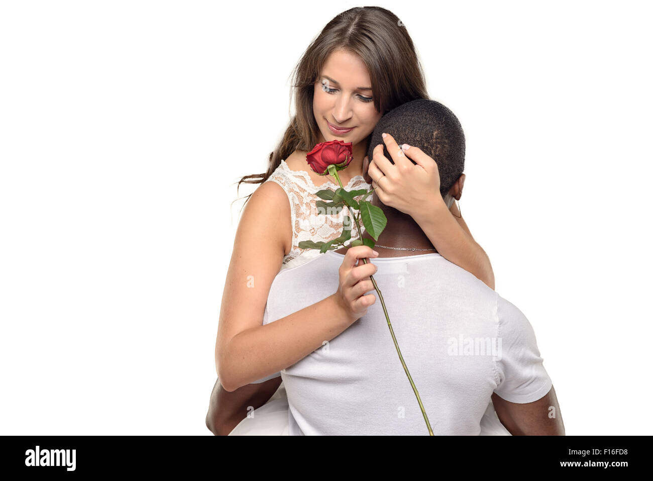 Sentimentale giovane donna che abbraccia il suo fidanzato o sweetheart come sorride teneramente verso il basso in corrispondenza di una singola rosa rossa ha appena dato h Foto Stock