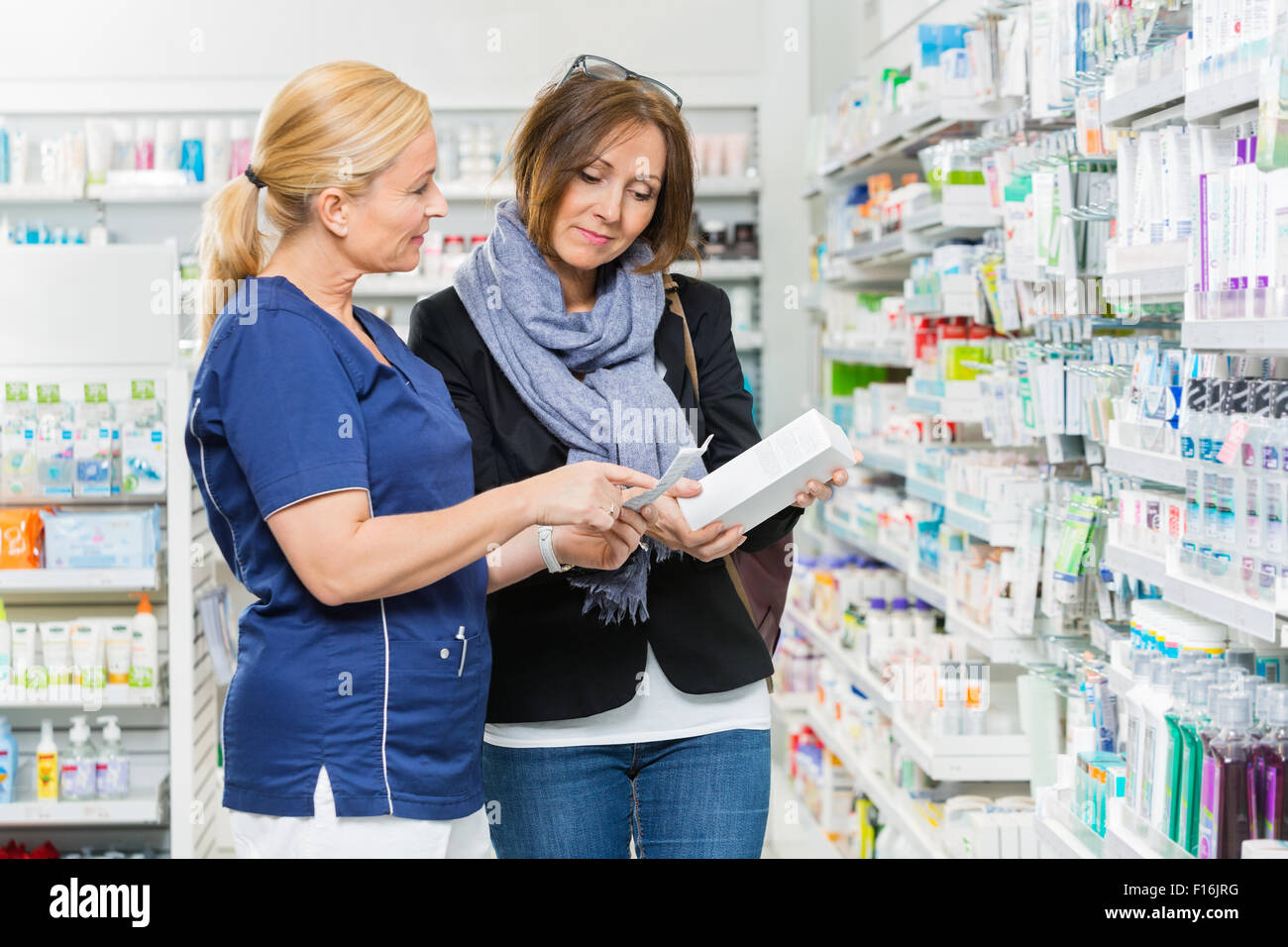 Il farmacista che spiega i dettagli del prodotto al cliente femmina Foto Stock