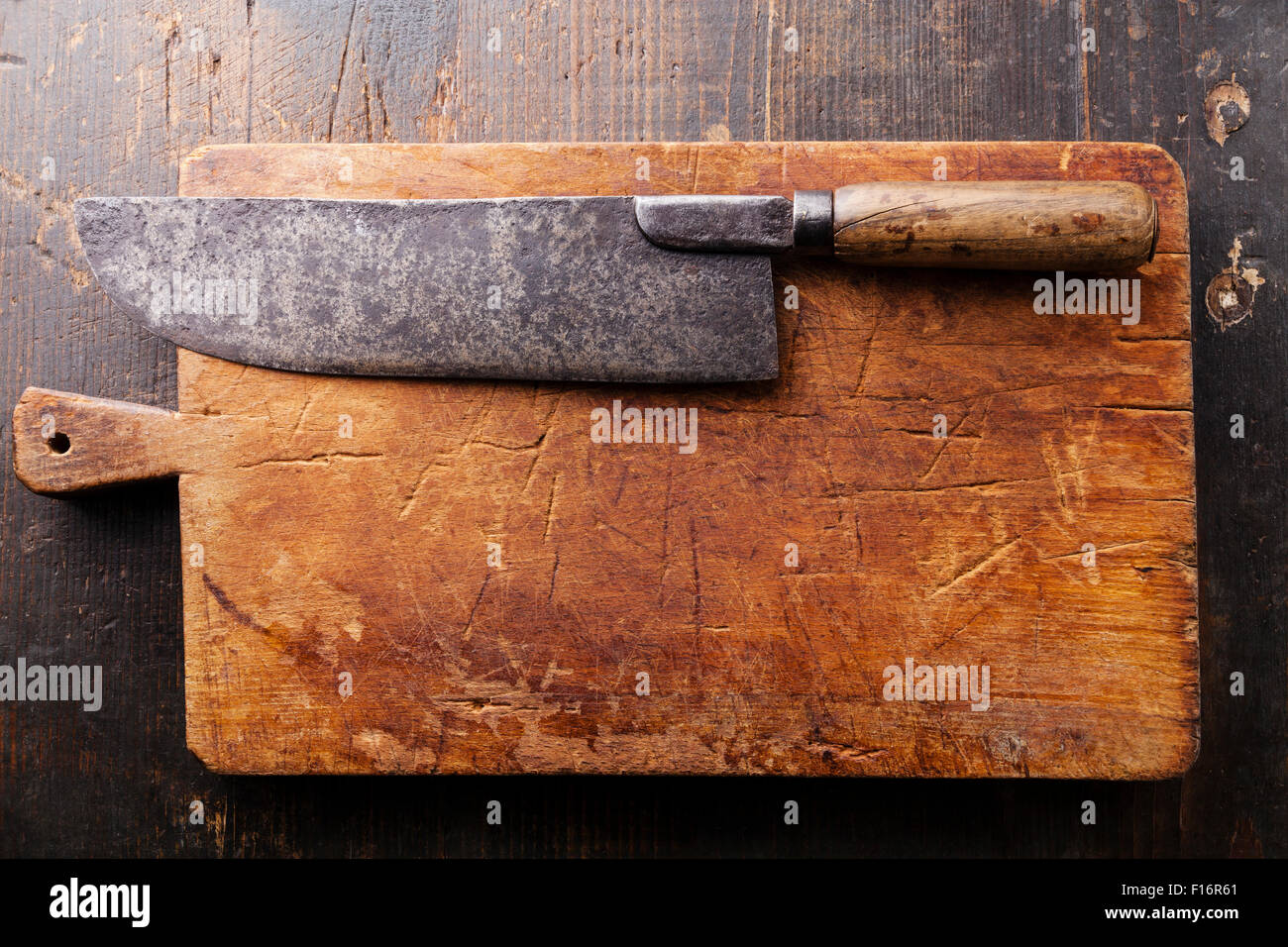 Tagliere e carne cleaver scuro su sfondo di legno Foto Stock