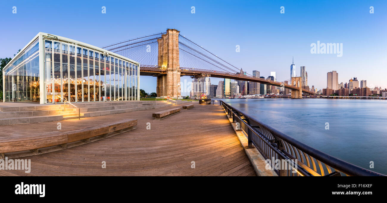 Il Ponte di Brooklyn e la parte inferiore di Manhattan skyline panorama di sunrise come vista dal Ponte di Brooklyn Park riverbank, in New York Foto Stock