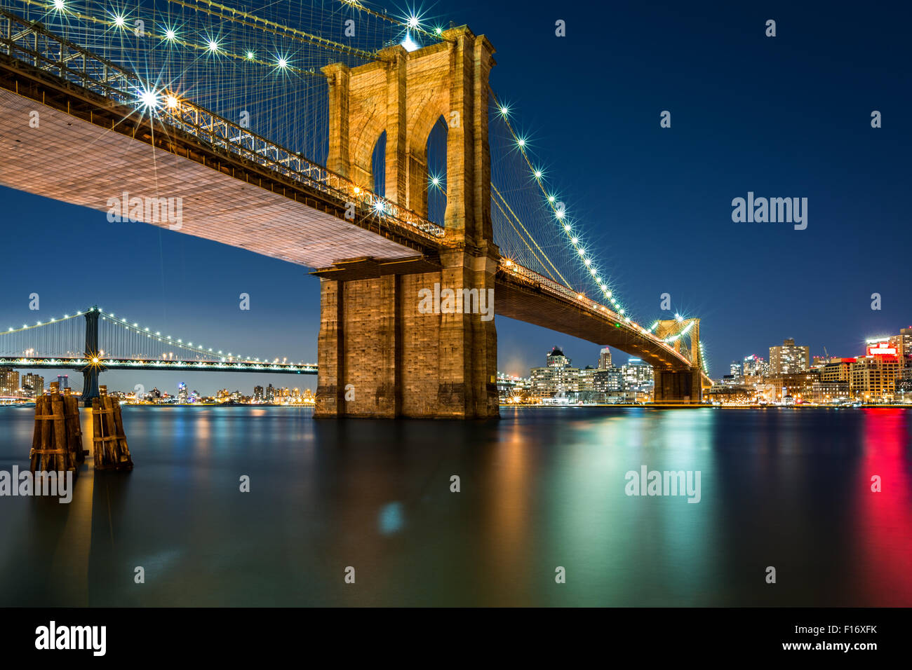 Illuminato il Ponte di Brooklyn da notte come visto dal lato di Manhattan - molto lunga esposizione per una superficie perfettamente liscia acqua Foto Stock