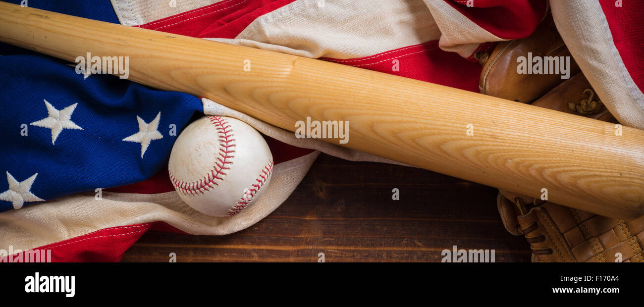 Un vecchio, antichi bandiera americana con vintage attrezzatura da baseball su una panca in legno Foto Stock
