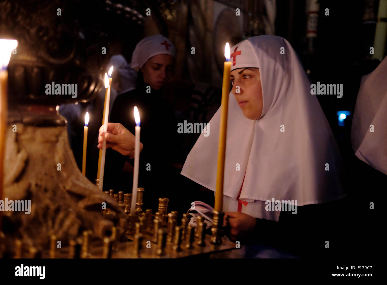 Una suora ortodossa cristiana illumina le candele mentre prega all'interno della Chiesa del Santo Sepolcro, nella città vecchia di Gerusalemme Israele Foto Stock