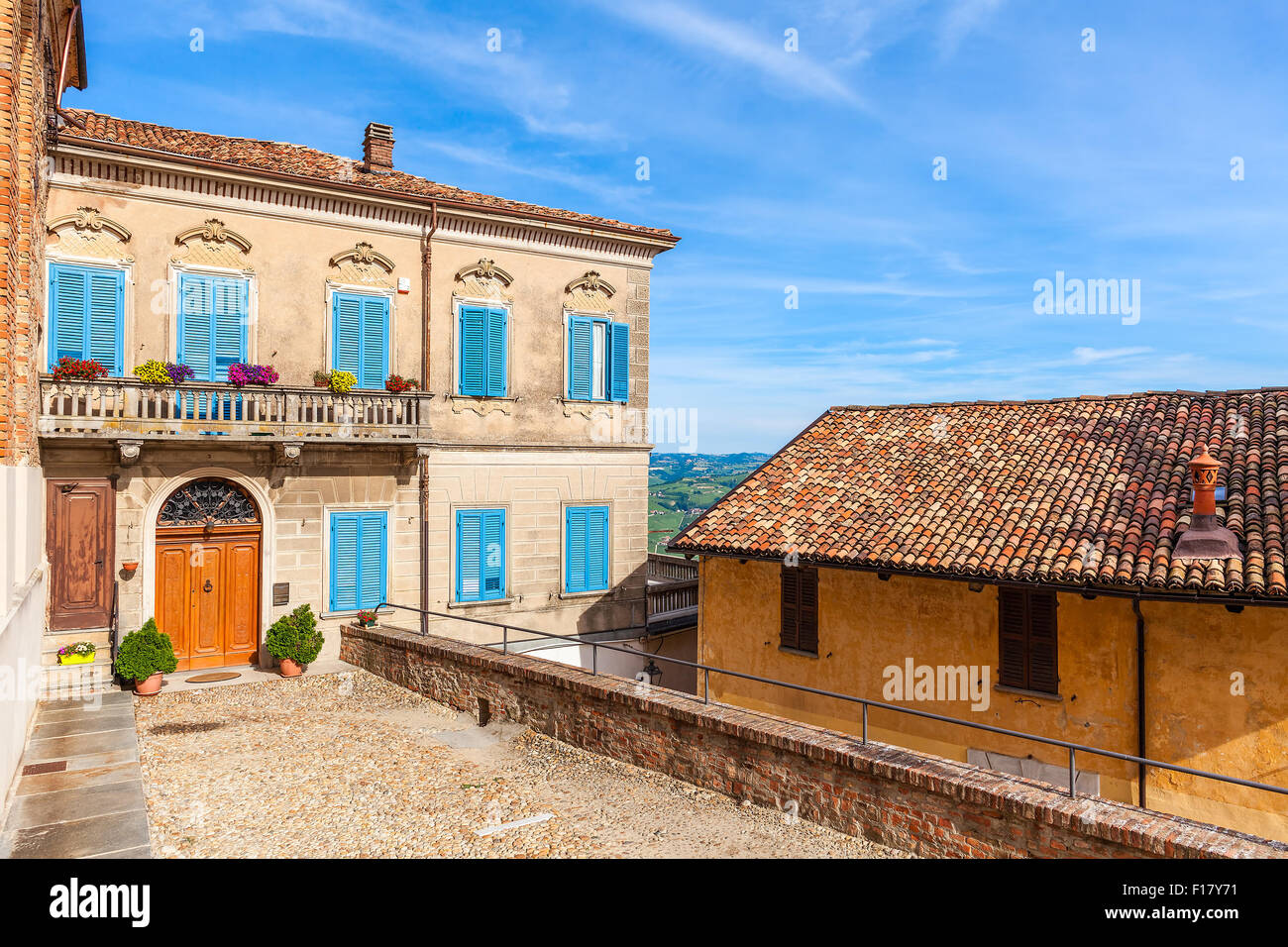 La facciata della casa colorati con persiane di legno sotto il cielo blu nella piccola città italiana in Piemonte, Italia settentrionale. Foto Stock