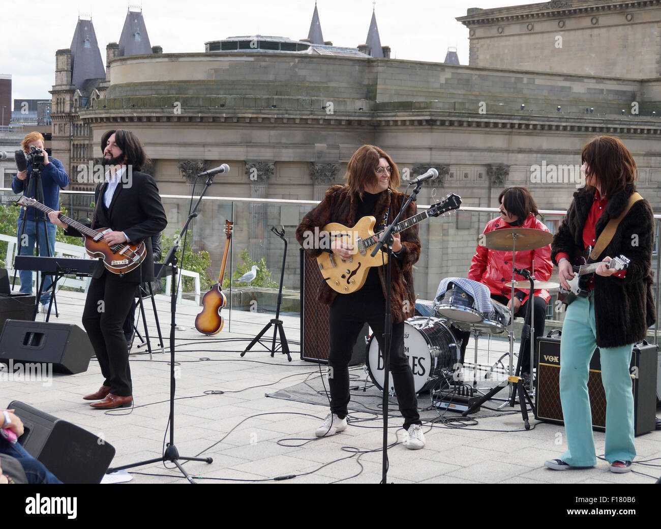 Liverpool, Regno Unito. Il 29 agosto, 2015. Essi Beatles, un scozzese Beatles tribute band, ricreato il Beatles ultima esecuzione pubblica sul tetto del quartier generale di Apple in 1969, giocando sulla sommità di Liverpool Central Library nel pomeriggio di sabato, 29 agosto. Esso è stato parte di International Beatles celebrazioni. Credito: Pak Hung Chan/Alamy Live News Foto Stock