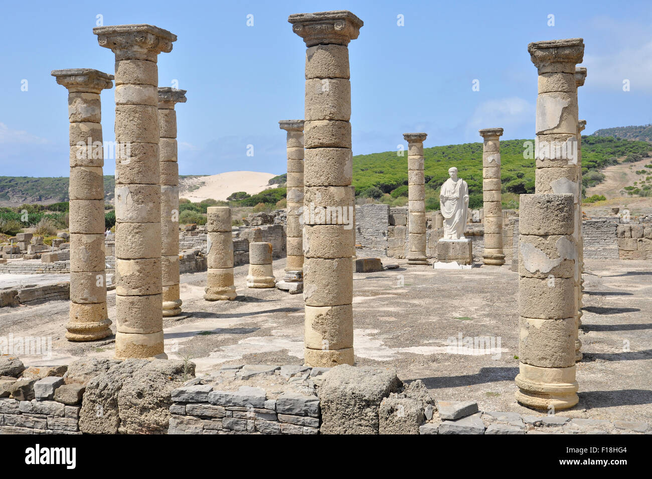 Palazzo di Giustizia delle rovine romane di Baelo Claudia con la statua di Traiano nella baia di Bolonia con dune di sabbia di Bolonia Beach all'estremità lontana (Tarifa, Cadice, Spagna) Foto Stock