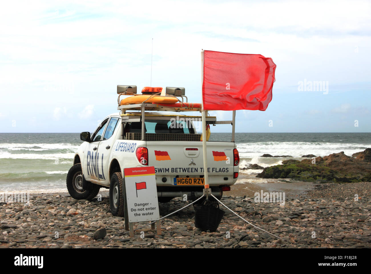 Una Toyota Hilux RNLI Lifeguard veicolo con una spia rossa bandiera che vieta la balneazione sulla spiaggia. Foto Stock