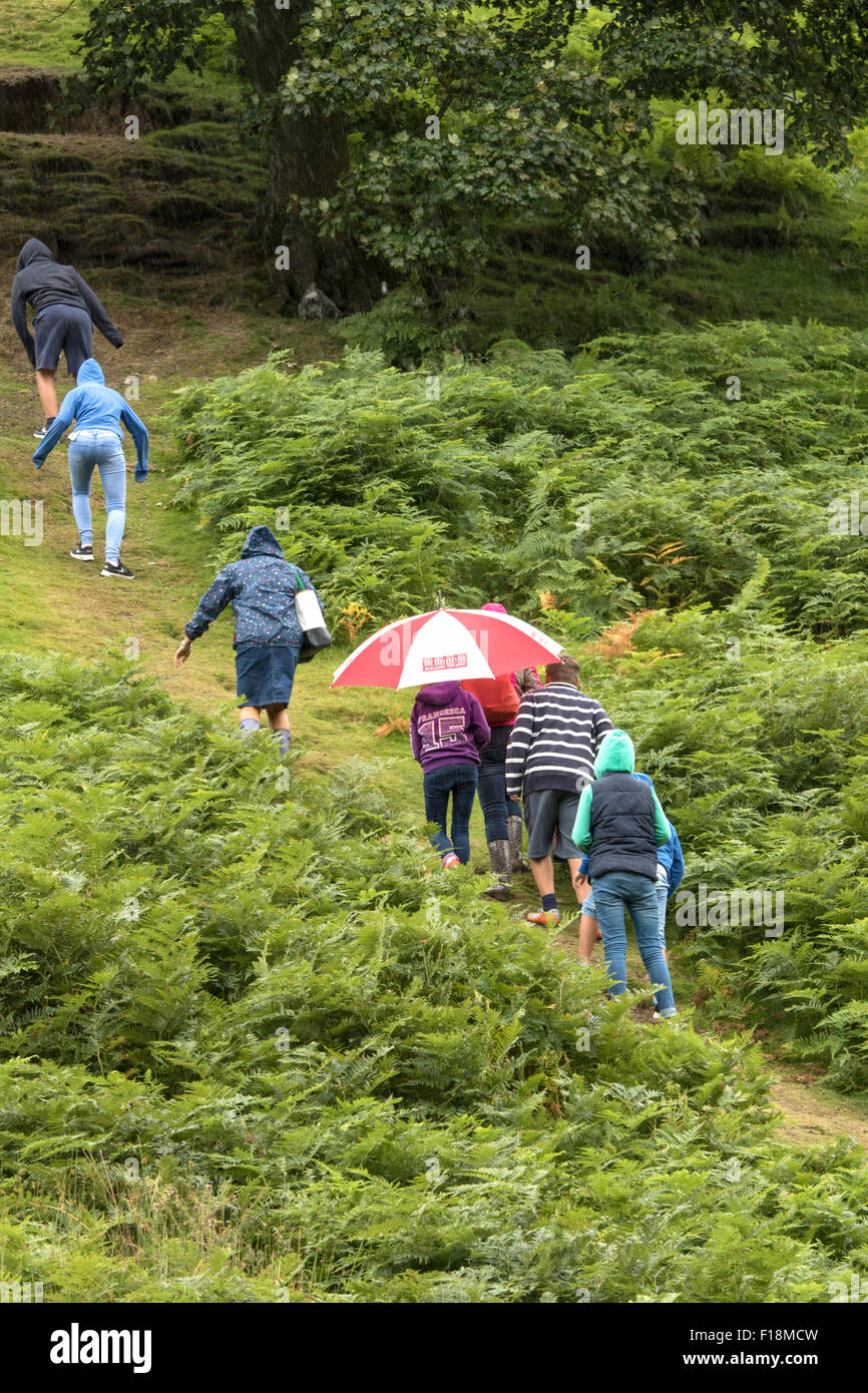 Famiglia salendo una collina sotto la pioggia in campagna britannica, England, Regno Unito Foto Stock
