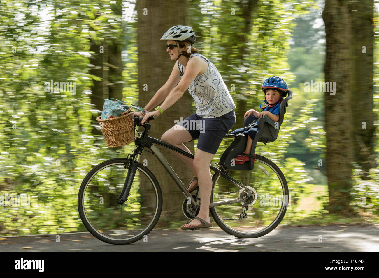 Signora escursioni in bicicletta con il bambino del vettore in campagna, England, Regno Unito Foto Stock