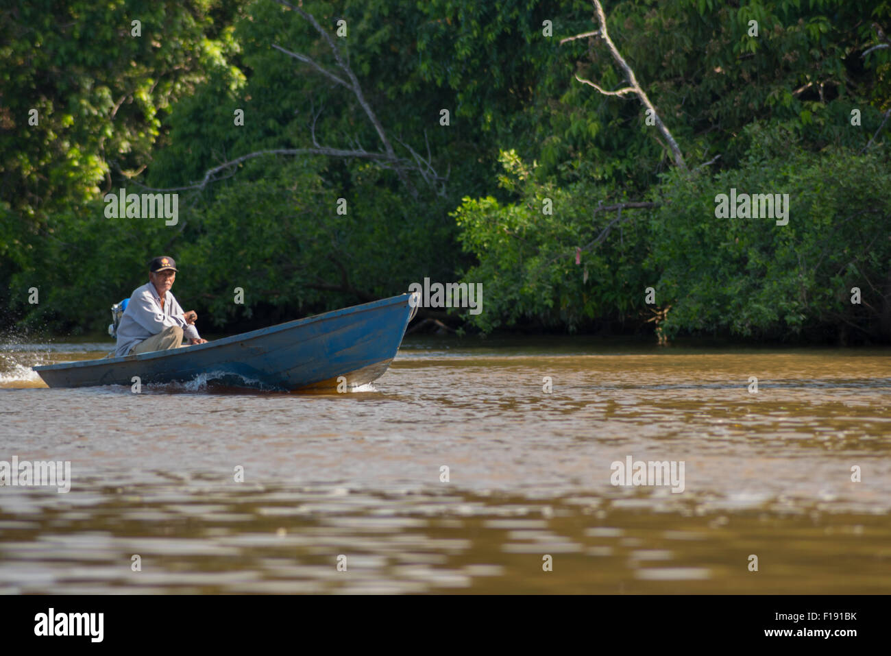 Un uomo anziano che viaggia su un battello fluviale che si muove sul fiume Sangatta a Kutai orientale, Kalimantan orientale, Indonesia. Foto Stock