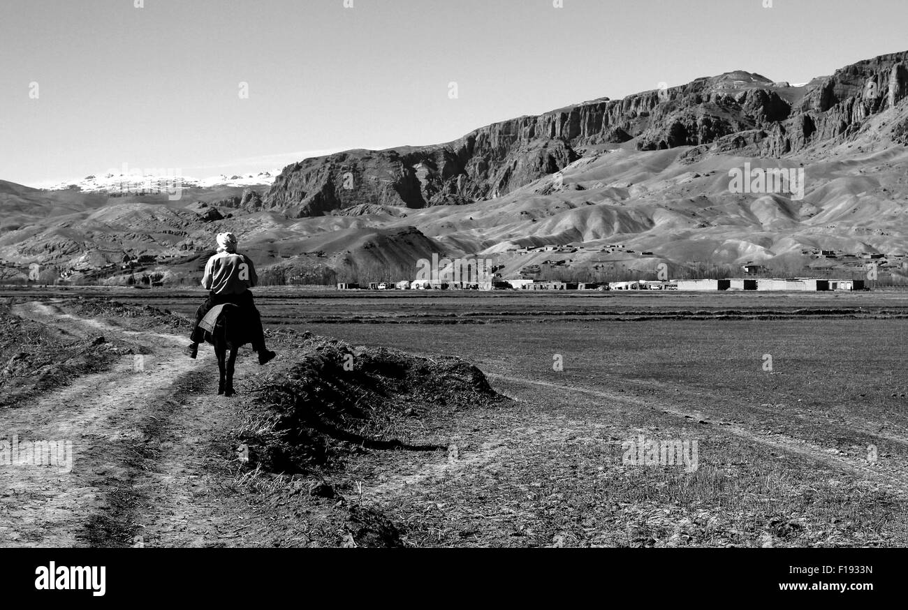 Lone uomo afgano in sella al suo asino per il villaggio di Solitario Foto Stock