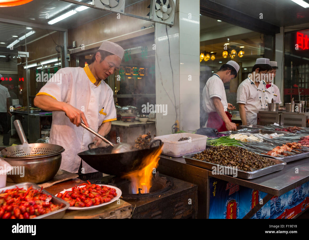 Cuoco prepara il cibo nel corso flaming wok al marciapiede stand alimentari nel Quartiere Musulmano di Xi'an, Cina Foto Stock