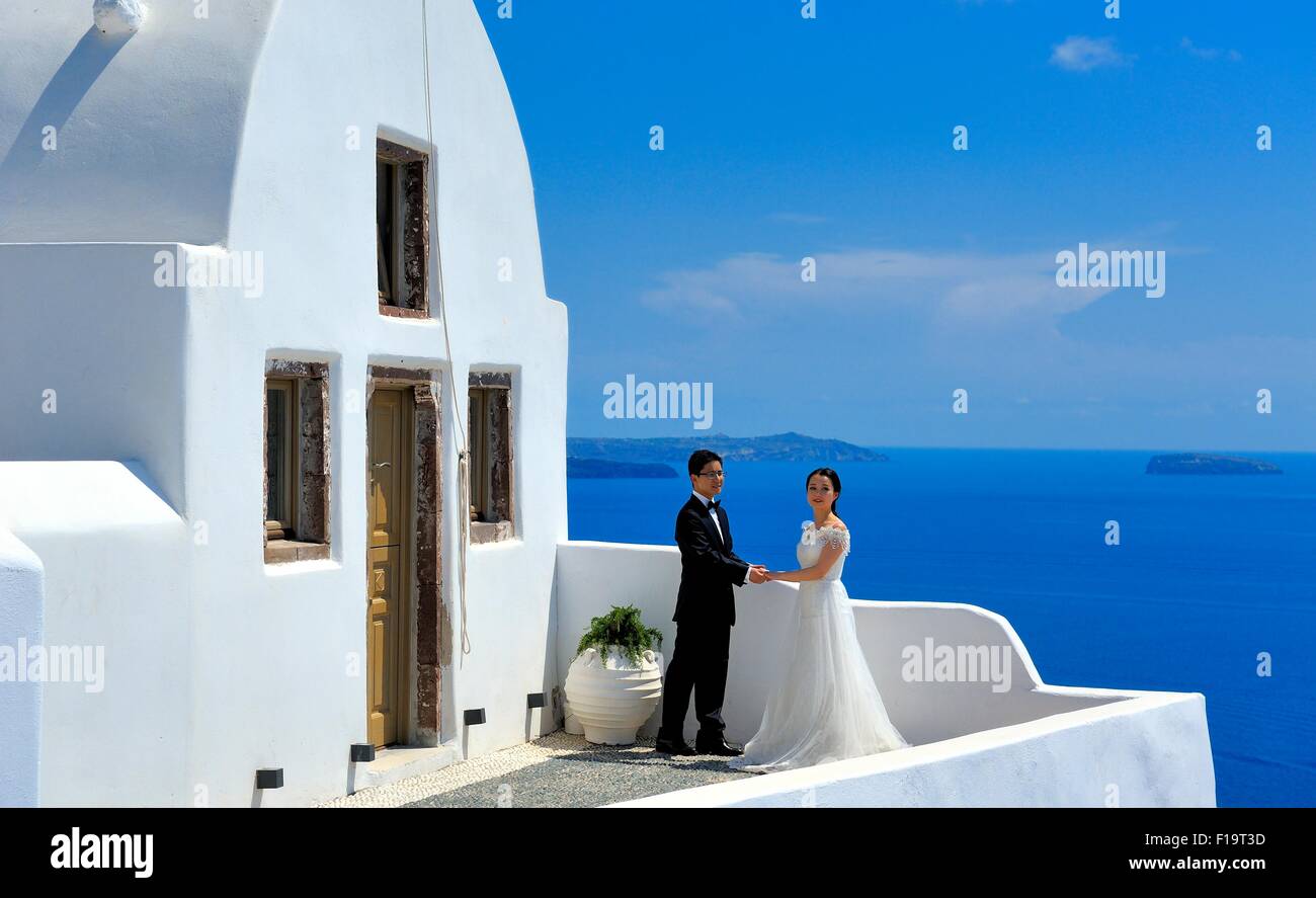 Una giovane coppia asiatica che posano per una foto fuori una chiesa sull isola di Santorini Grecia Foto Stock