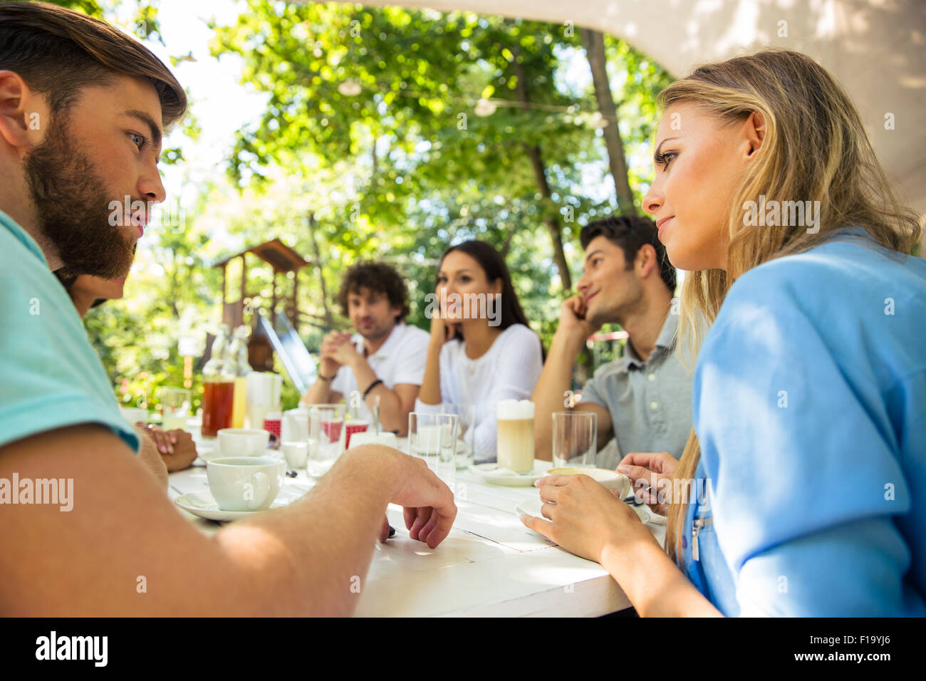 Il gruppo di un felice amici seduti al tavolo nel ristorante all'aperto Foto Stock