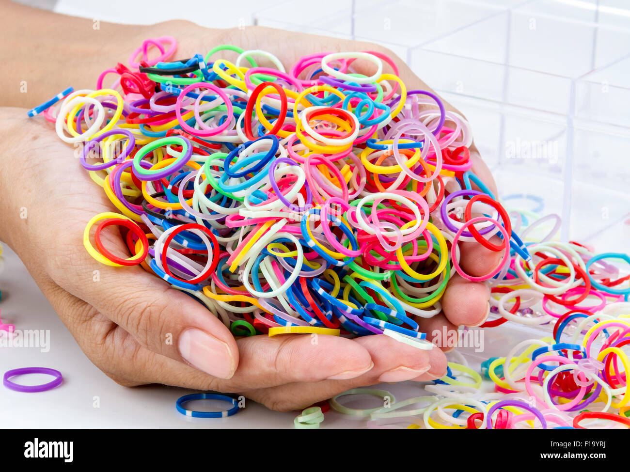 Mani e pila di rotondo piccolo gomma colorata bande di colore arcobaleno per  rendere rainbow telaio braccialetti sul tavolo Foto stock - Alamy