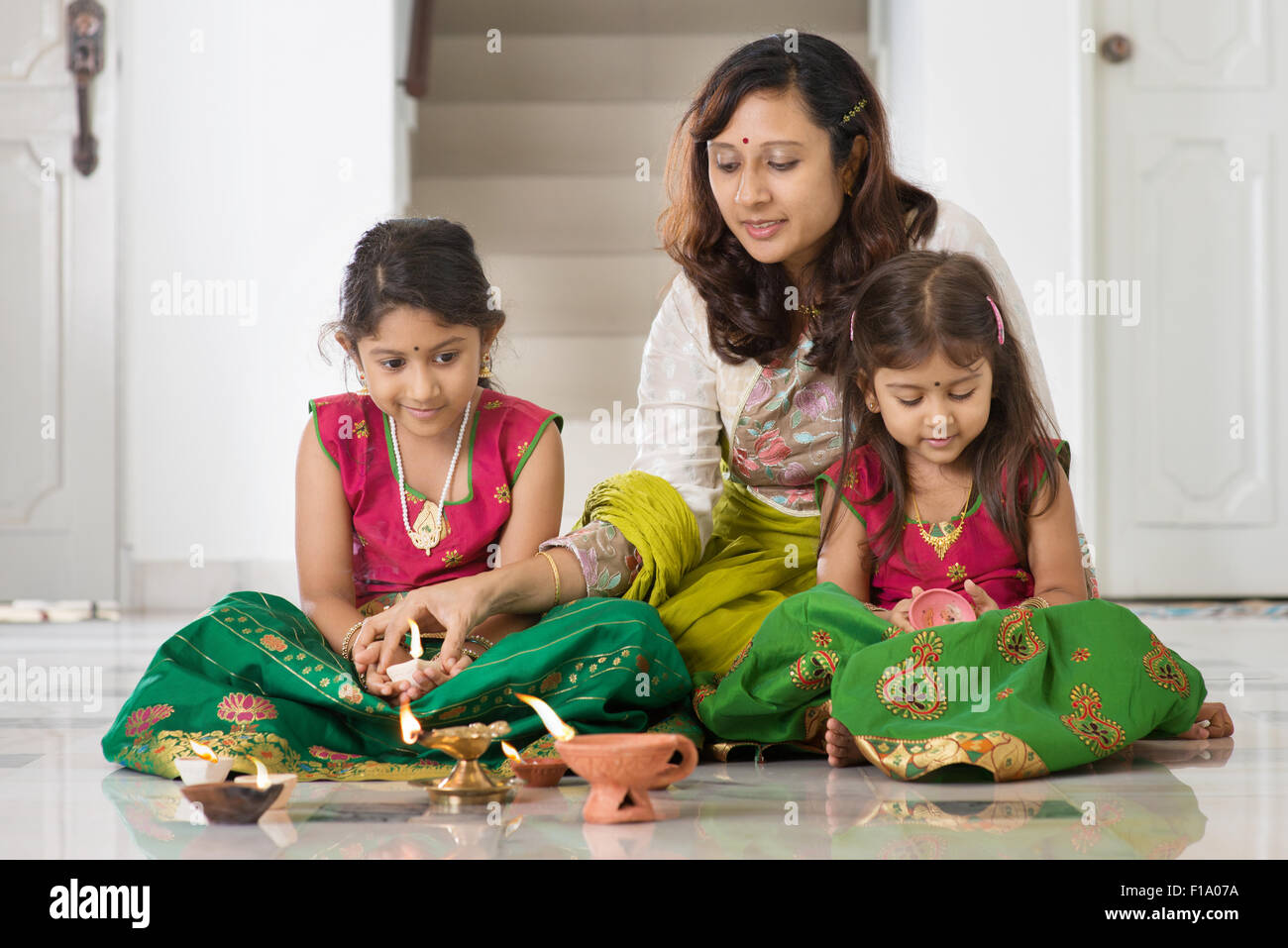 Famiglia indiana nel tradizionale sari olio di illuminazione con lampada e celebrare Diwali, fesitval di luci a casa. Foto Stock