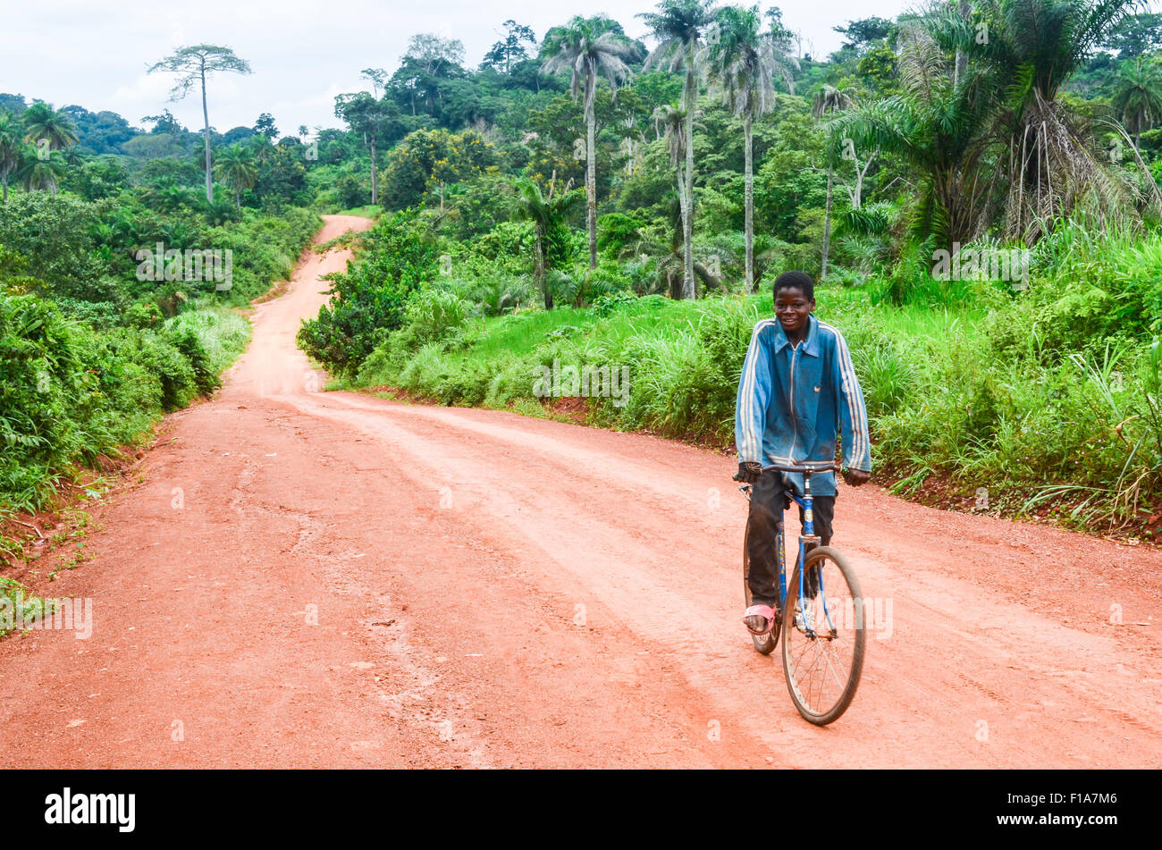 Ragazzo africano ciclismo su strada sterrata con una vecchia bicicletta Foto Stock