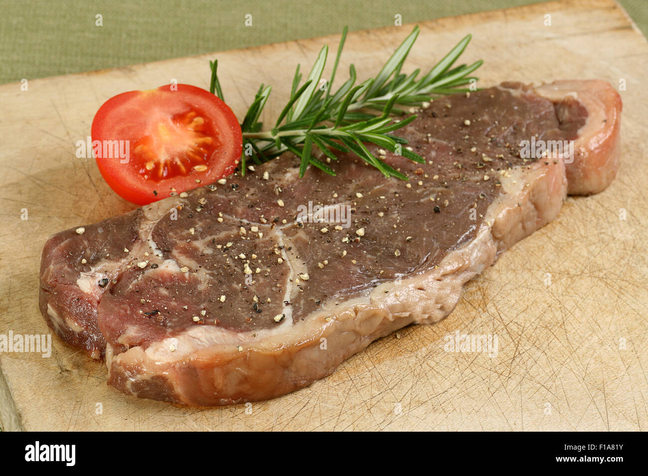 Età bistecca di controfiletto non cotti con rosmarino e pomodoro Foto Stock