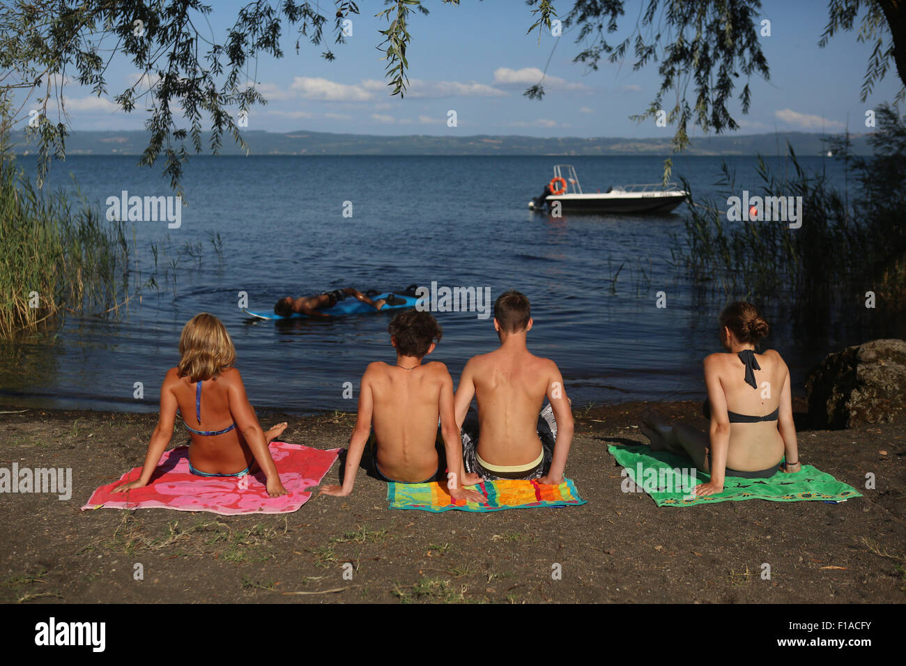 Il lago di Bolsena, Italia, giovani seduti sulla riva del lago di Bolsena Foto Stock