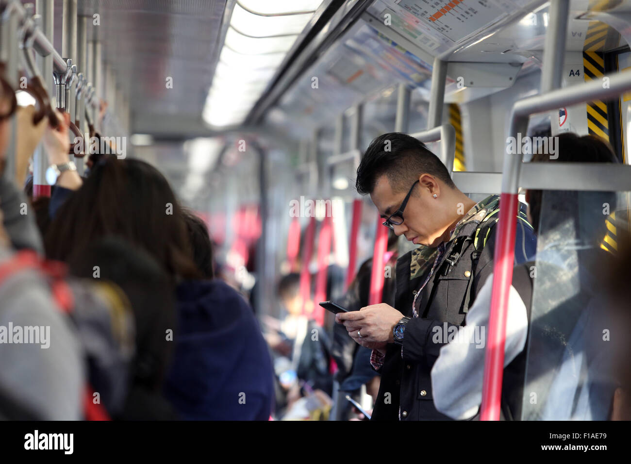 Hong Kong, Cina, uomo che guarda alla metropolitana vano sul suo smartphone Foto Stock