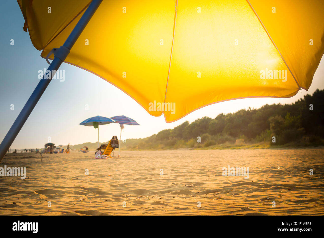 Ombrello giallo sulla spiaggia di giorno di estate al tramonto Foto Stock