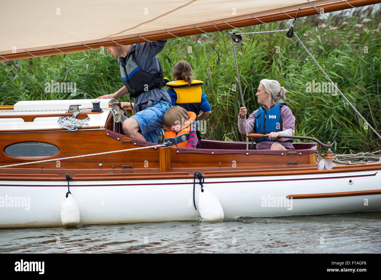 Una famiglia vela una Norfolk Broads barca a vela verso il basso attraverso una delle dighe sul modo di Potter Higham Foto Stock