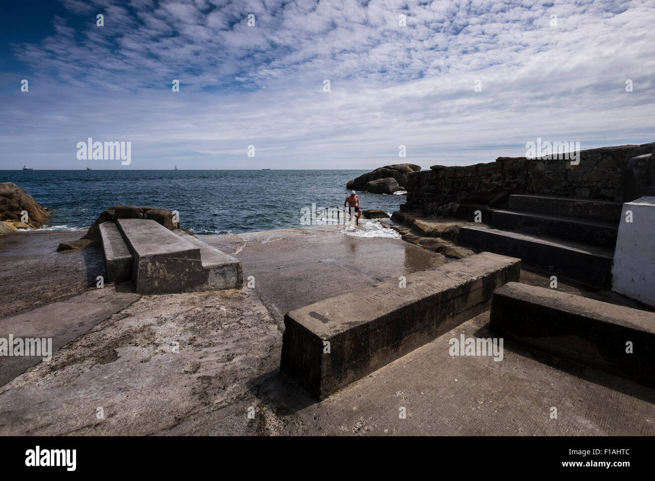 Nuotatore di uscire dal mare presso la piscina Fortyfoot luogo a Sandycove, Dublino, Irlanda. Foto Stock
