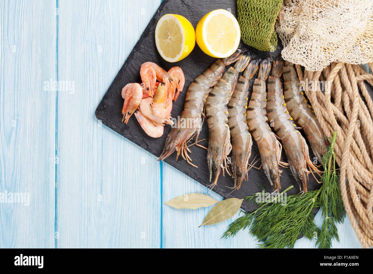 Crudo fresco gamberoni e attrezzature per la pesca su un tavolo di legno. Vista da sopra con lo spazio di copia Foto Stock