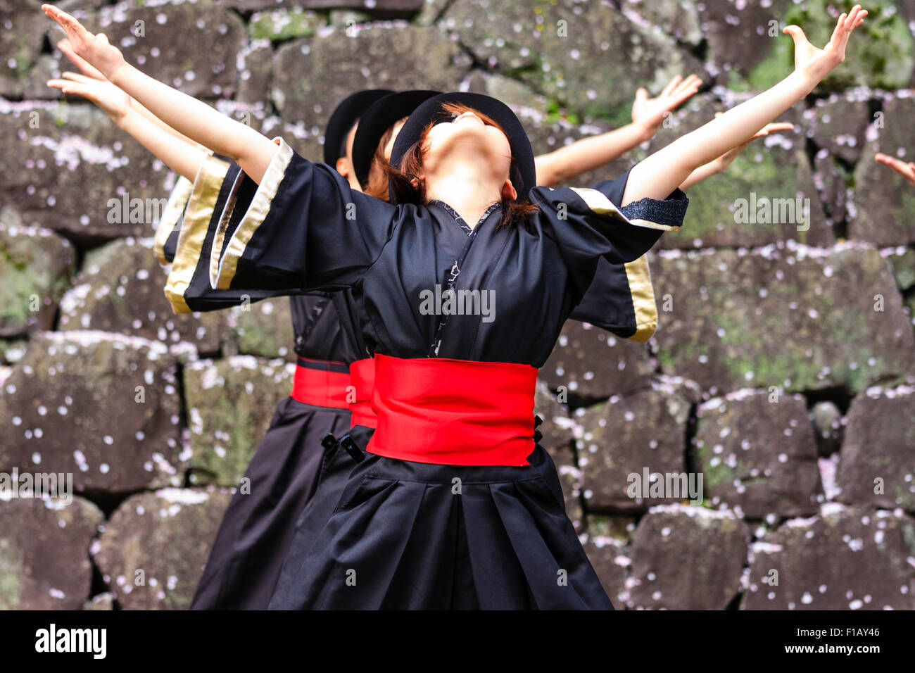 Giapponese Yosakoi Dance. Dance Troupe, Fila di giovani donne che indossano yukata nero giacche, cappelli rossi e anta, dancing in una linea, di fronte, vicino. Foto Stock