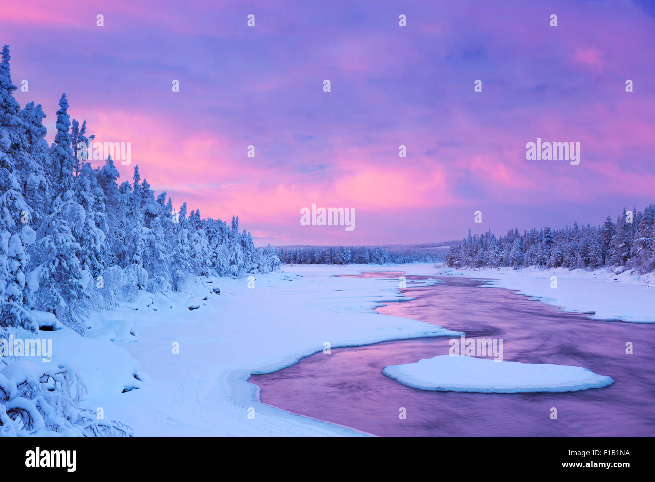 Un rapido in un fiume in inverno a sunrise. Fotografato alla Äijäkoski rapide nel fiume Muonionjoki in Lapponia finlandese. Foto Stock
