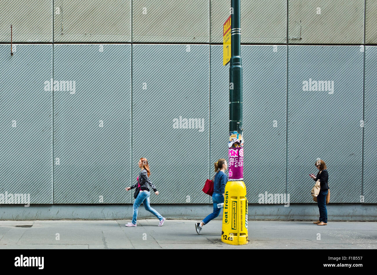 Tre giovani donne a camminare in una strada di città, uno guardando il suo smartphone Foto Stock