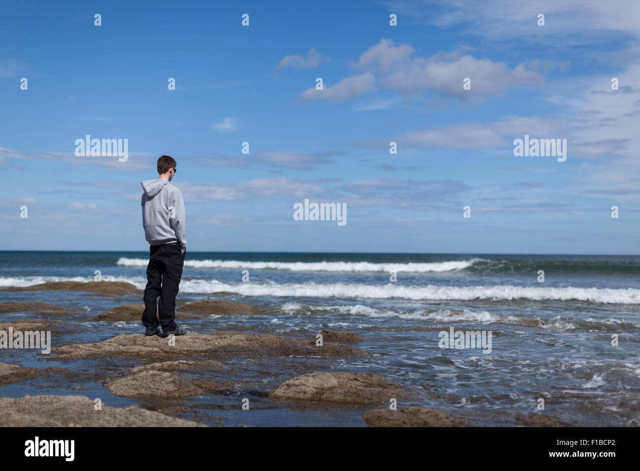 Un ragazzo adolescente guarda fuori al mare. Foto Stock