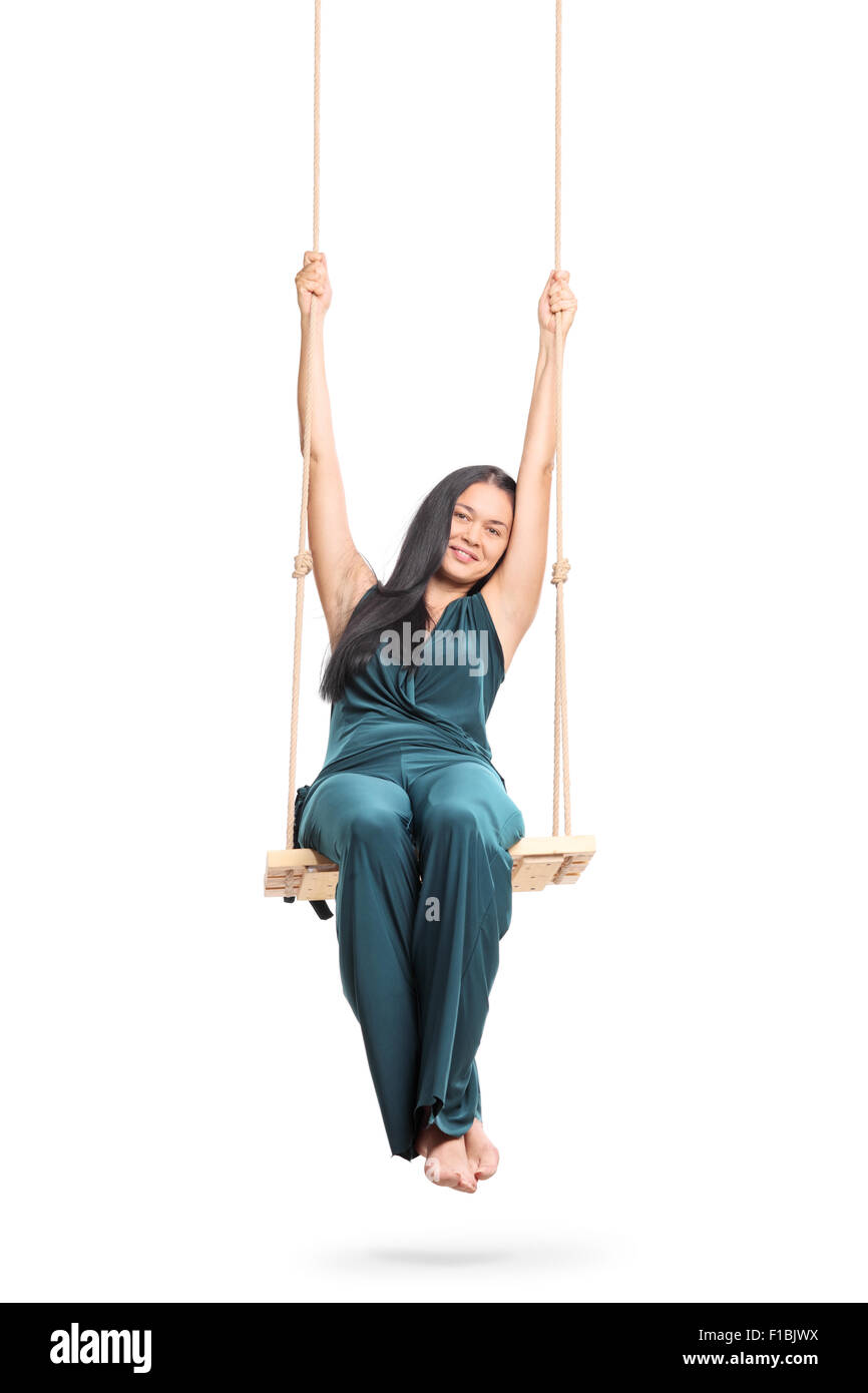 Lunghezza completa il ritratto di una donna seduta su una tavola di legno swing e guardando la telecamera isolata su sfondo bianco Foto Stock