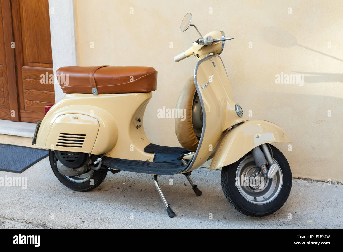 Gaeta, Italia - 19 agosto 2015: Classica giallo scooter Vespa parcheggiata sorge in prossimità della parete Foto Stock