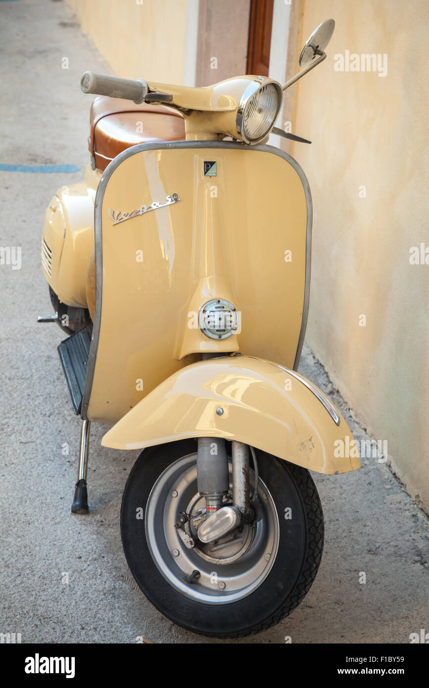 Gaeta, Italia - 19 agosto 2015: Classico giallo scooter Vespa parcheggiata sorge in prossimità della parete verticale della foto Foto Stock