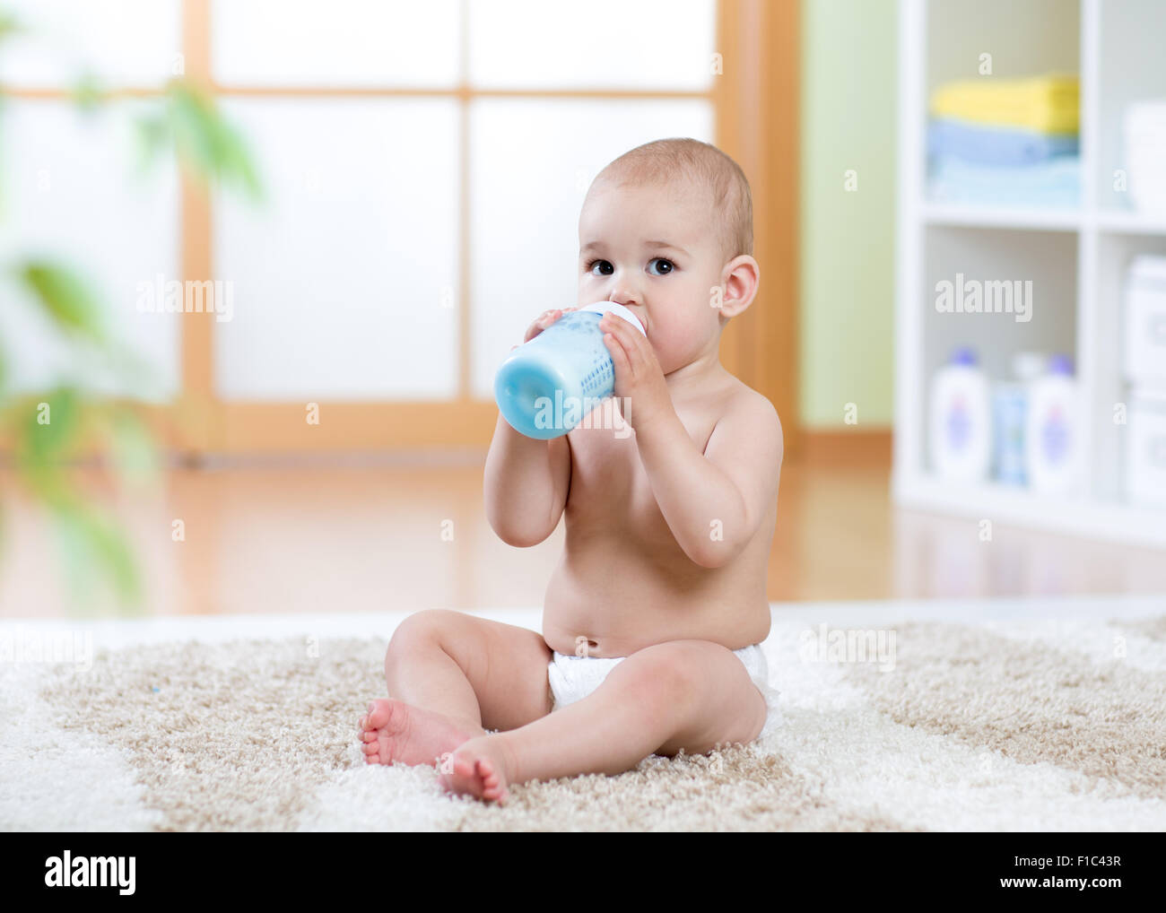 Sweet Baby tenendo la bottiglia e bere latte Foto Stock