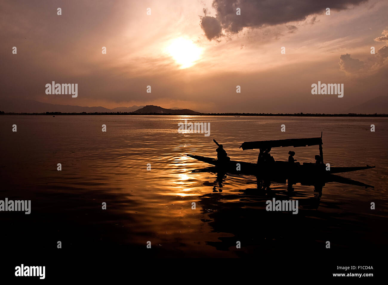 Shikara una barca dal lago, Srinagar con persone di silhouette al tramonto con sfumature di colore giallo Foto Stock