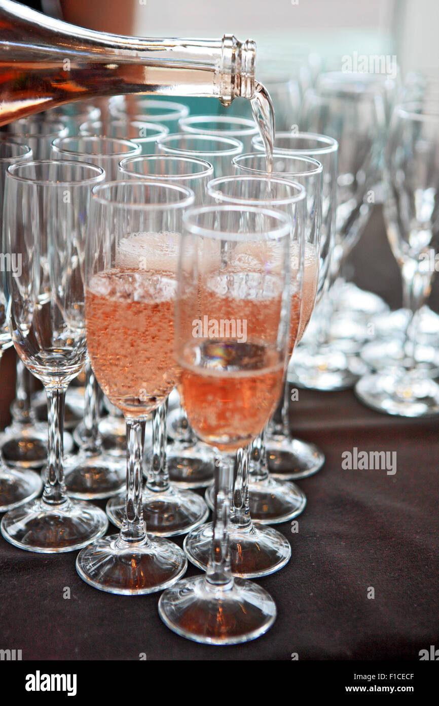 Champagne rosato essendo versata in champagne flauti Foto Stock